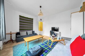 Ein modernes Wohnzimmer mit einer Couch, einem Holztisch, einem Fernseher und einem gemusterten Teppich.