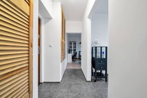 A hallway with a wooden door, a desk with a fan, and a bookshelf in the background. - Warsaw Downtown Studio- Top location, Metro Nearby (Warsaw)
