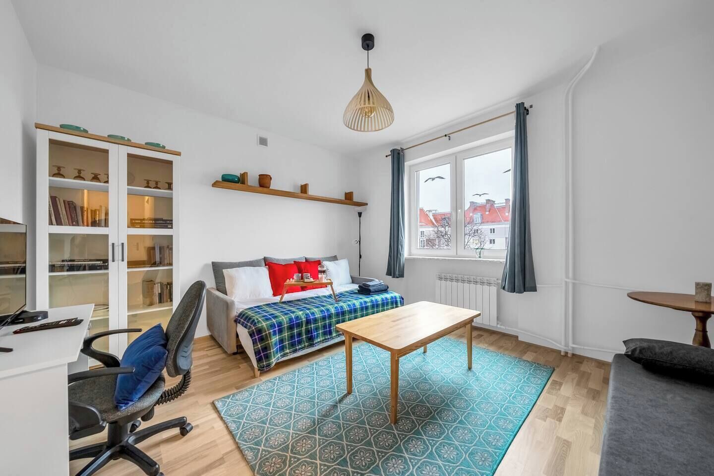 A modern room with a sofa, a small table, a desk, and a bookshelf.