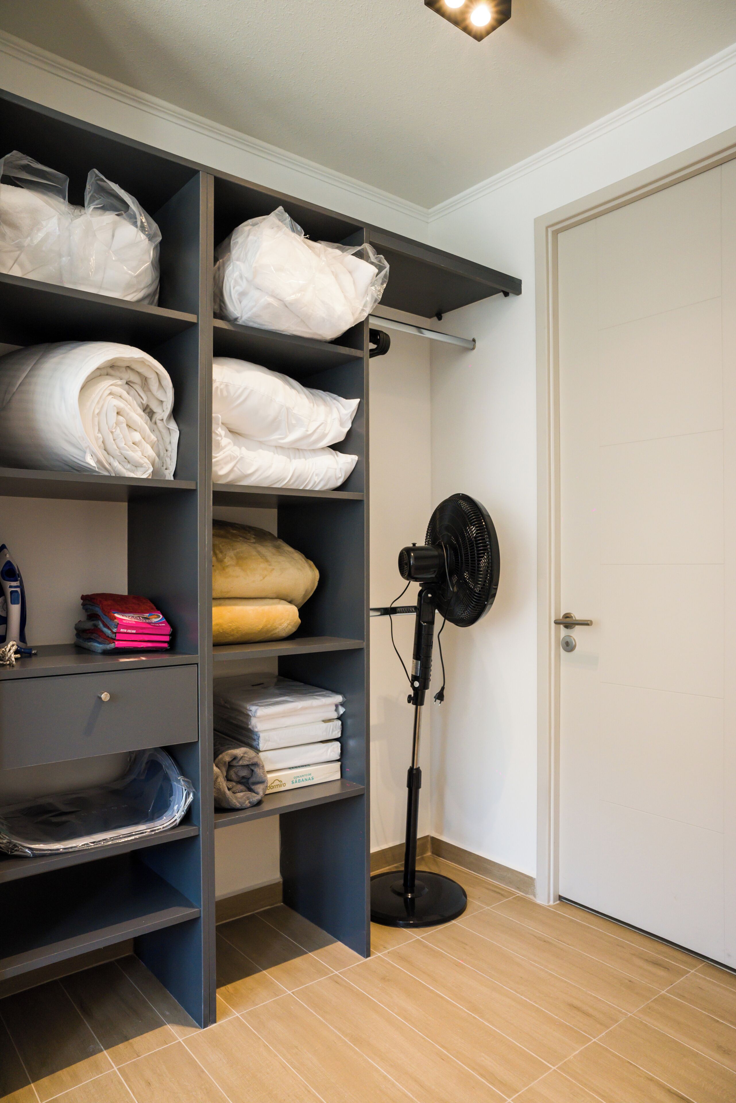 Ein Zimmer mit Einbauschrank, Standventilator und einer Tür.