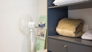 A room with a bed, a fan, and a shelf with folded towels and a blanket. - Inés Matte Urrejola Apartments by Andes STR (Providencia)