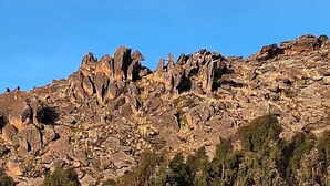 A rugged mountain landscape with rocky formations and sparse vegetation.