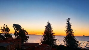 A coastal view with buildings and trees at sunset.