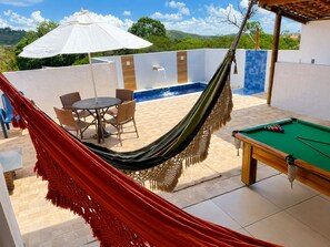 A poolside area with a hammock, pool table, and outdoor seating.