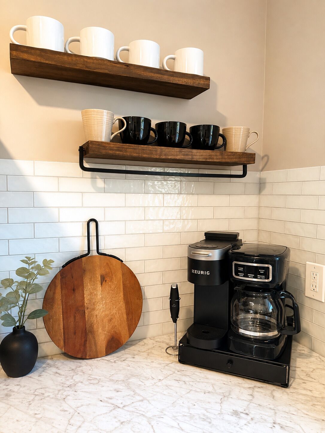 A kitchen with a coffee maker, a hanging pot, and shelves with mugs.