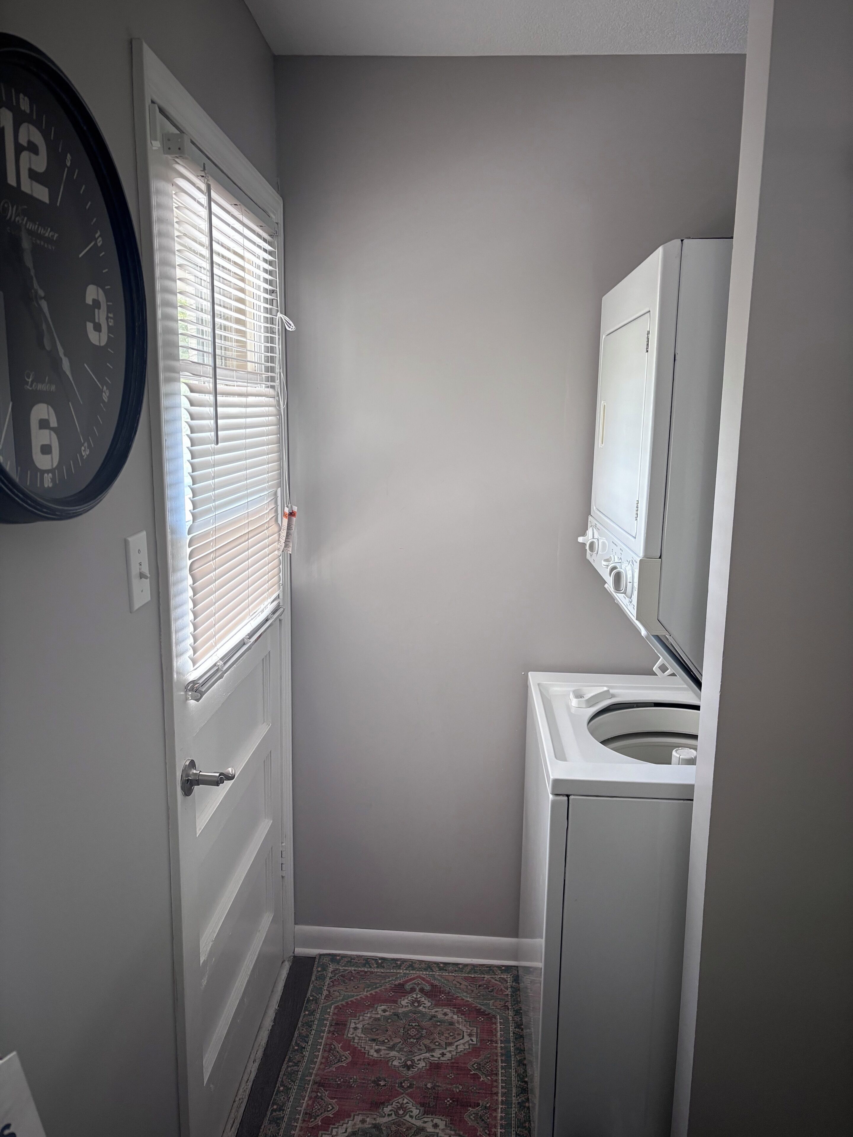 A compact bathroom with a toilet, a sink, and a clock on the wall.