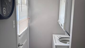 A compact bathroom with a toilet, a sink, and a clock on the wall.