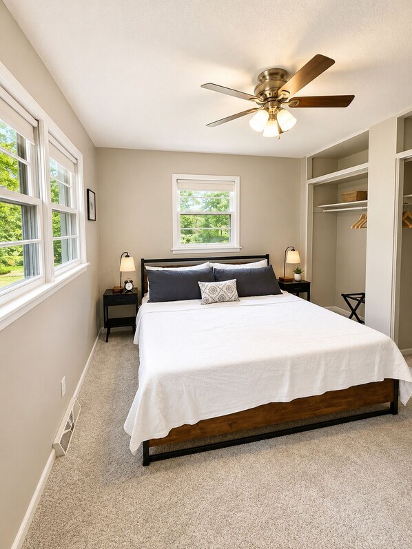 A bedroom with a bed, a ceiling fan, a window, and a walk-in closet.