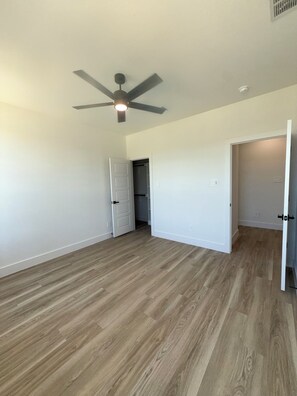 A room with wooden flooring, a ceiling fan, and white walls. - Arlington Park Estate - 3BR Luxury [Coming Soon!] (Dallas)