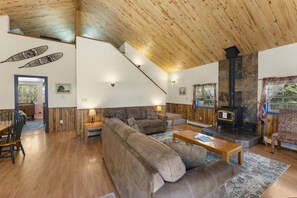Ein geräumiger Wohnbereich mit hoher Holzbalkendecke, Kamin und einer Treppe zu einer oberen Ebene.
