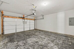 A garage with a concrete floor, a wooden beam ceiling, and a white garage door. - New & Modern 3BR/2BA | Family-Friendly Wilmington (Wilmington)