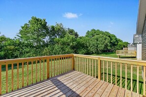 A wooden deck with a railing, surrounded by a grassy yard and trees. - New & Modern 3BR/2BA | Family-Friendly Wilmington (Wilmington)