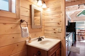 A wooden interior with a sink, mirror, and towel rack. - Coyote Cabin | Cozy Mountain Retreat (South Fork)