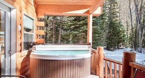 A wooden cabin with a hot tub on a porch, surrounded by trees and a snowy landscape. - Coyote Cabin | Cozy Mountain Retreat (South Fork)