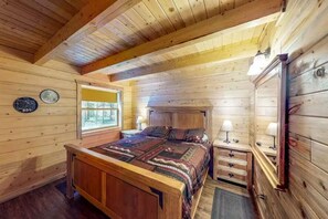 A wooden cabin bedroom with a bed, bedside tables, and a window. - Coyote Cabin | Cozy Mountain Retreat (South Fork)