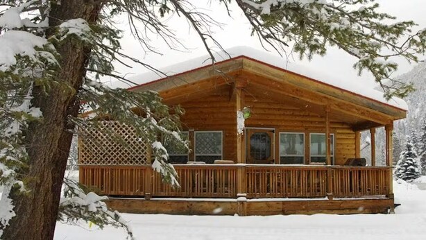 A wooden cabin with a porch, surrounded by snow-covered trees. - Sequoia Cabin | Waterfront Escape with Private Hot (South Fork)