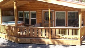 A wooden cabin with a covered porch, a hot tub, and a grill area. - Sequoia Cabin | Waterfront Escape with Private Hot (South Fork)