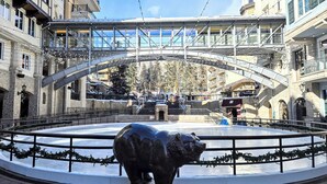 A public square with a central fountain, surrounded by stone buildings with balconies, under a pedestrian bridge. - 1 BR+ sofabed & fireplace, walk to Village, Shuttle, Hot Tubs, 3/21-27/2027 ONLY (Vail)