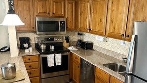A modern kitchen with wooden cabinets, stainless steel appliances, and granite countertops. - 1 BR+ sofabed & fireplace, walk to Village, Shuttle, Hot Tubs, 3/21-27/2027 ONLY (Vail)