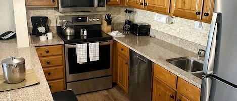 A modern kitchen with wooden cabinets, stainless steel appliances, and granite countertops.