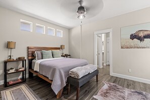 A bedroom with a wooden bed, bedside lamps, a rug, and a wall-mounted ceiling light. - Southeast Boise Deluxe Home (Boise)