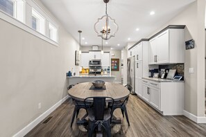 A modern kitchen with white cabinetry, a central island with seating, and a chandelier.