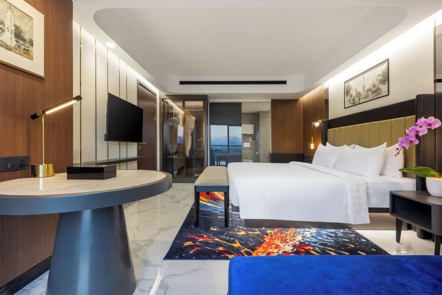 A modern hotel room with a bed, bedside table, and a view of a cityscape.
