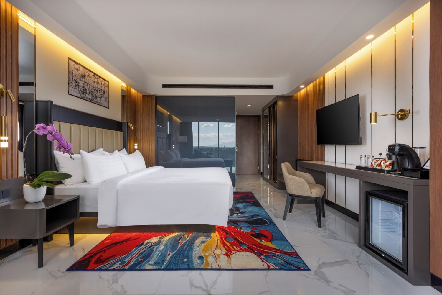 Une chambre d’hôtel moderne équipée d’un lit, d’un bureau, d’une télévision et offrant une vue sur l’extérieur.