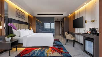Une chambre d’hôtel moderne équipée d’un lit, d’un bureau, d’une télévision et offrant une vue sur l’extérieur.