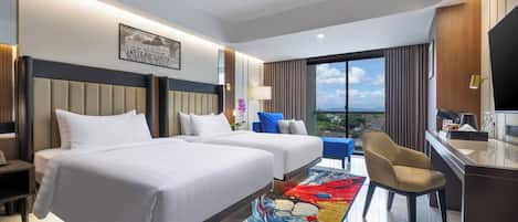 A hotel room with two beds, a desk, a chair, a TV, and a large window with a city view.