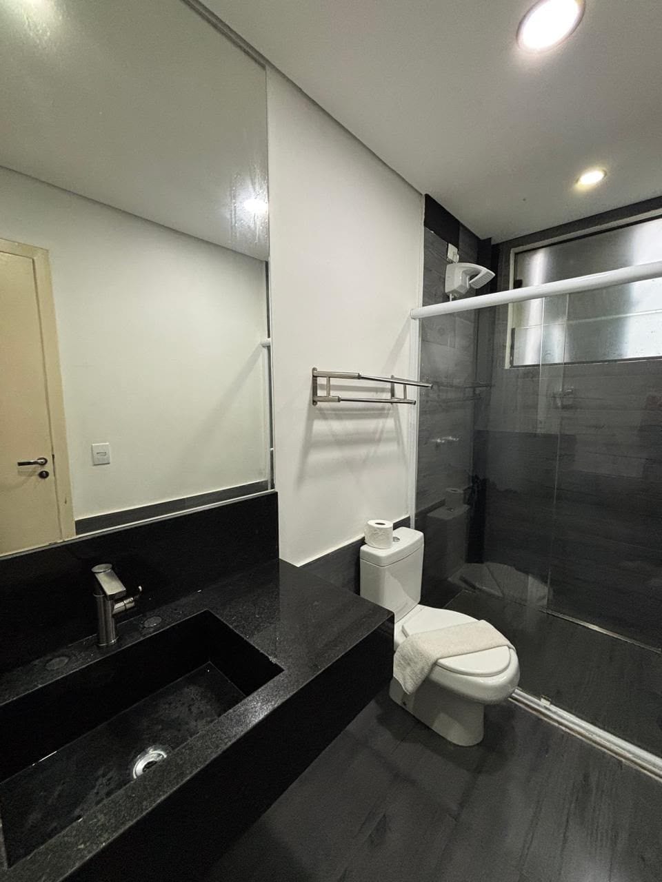 Un baño moderno con lavamanos, inodoro y cabina de ducha de vidrio, todos en color negro.
