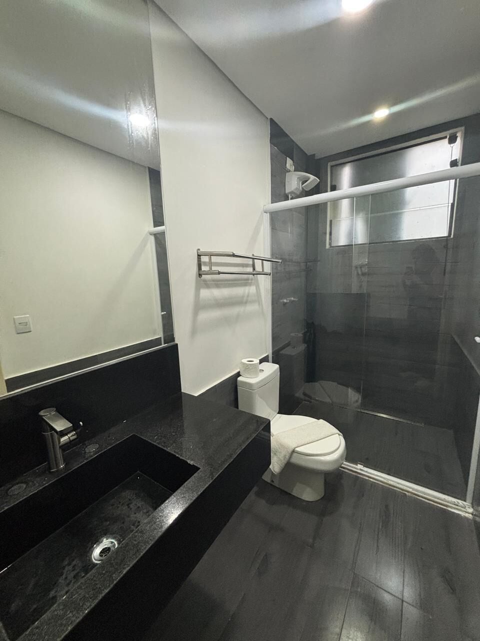 A modern bathroom with a black sink, white toilet, and a glass shower enclosure.