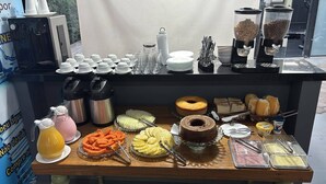 Una mesa de buffet con diversas opciones de comida, incluyendo pasteles, bollería y bebidas.