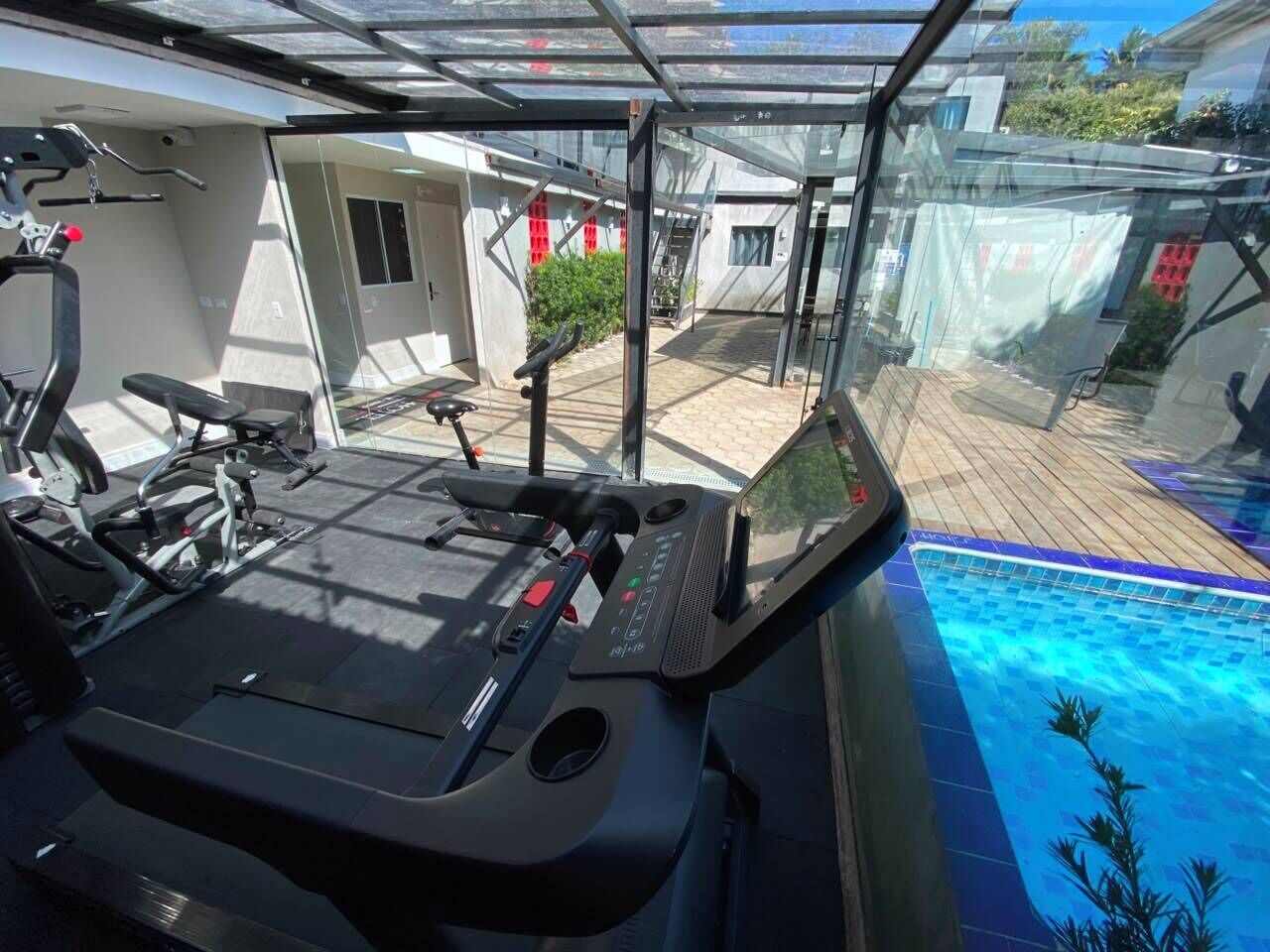 Uma academia em casa com equipamentos de ginástica e vista para uma piscina.