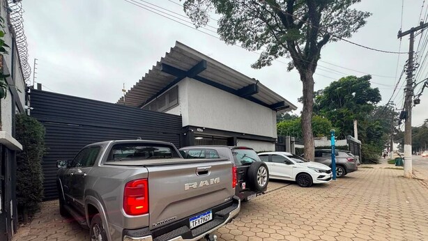 A residential street with parked vehicles, including a grey Ram pickup truck and a white car. - ADD HOTÉIS MORUMBI (São Paulo)