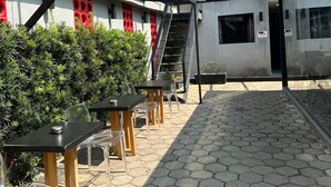 An outdoor seating area with hexagonal tiles, clear plastic chairs, and tables.