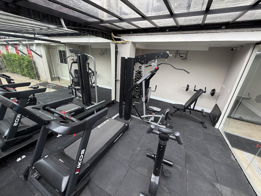 Ett gym med löpband, styrketräningsmaskiner och en motionscykel som är monterad på väggen.