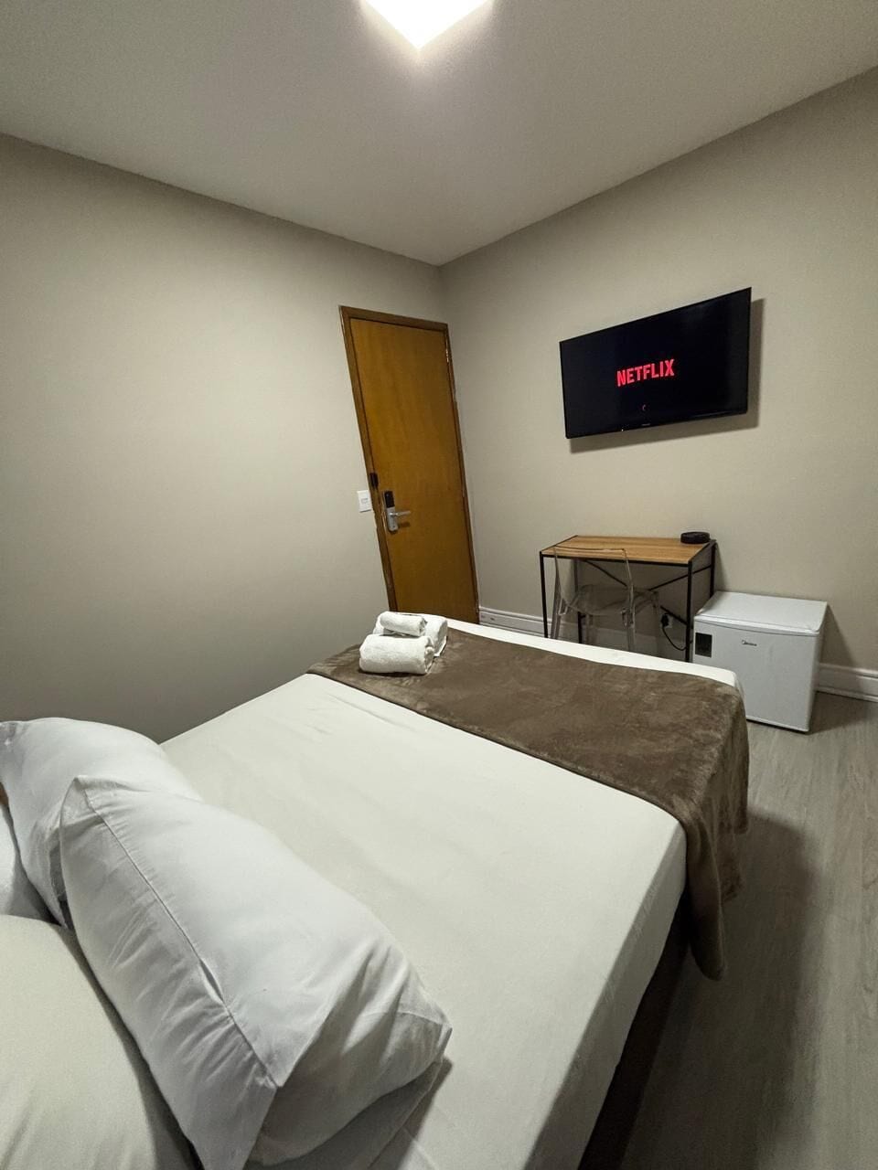 Een hotelkamer met een bed, een bureau, een televisie en een deur.