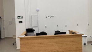 A reception desk with a wooden finish, a white wall with the word 'LAGOA' above it, and a reception area with chairs and a counter.