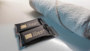 Two packages labeled "Rede Andrade Hotéis" on a white surface next to a rolled towel.