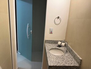 Baño con lavamanos de encimera de granito, toallero y puerta que da a otra habitación.