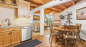 A kitchen with wooden cabinets, a dishwasher, and a dining area with a round table and chairs. - Cozy 2 Bedroom Condo in Silverthorne, CO! (Silverthorne)
