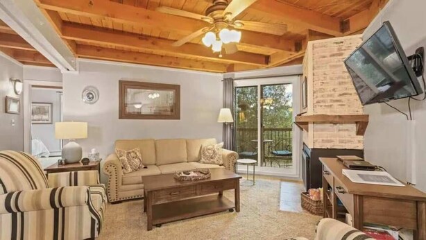 A cozy living room with a sofa, armchairs, a coffee table, a fireplace, and a television mounted on the wall. - Cozy 2 Bedroom Condo in Silverthorne, CO! (Silverthorne)