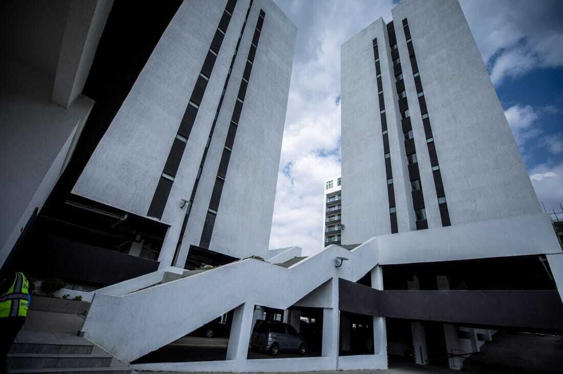 Un bâtiment moderne doté d’une conception architecturale unique, caractérisé par deux structures imposantes aux lignes verticales et un escalier menant à l’entrée.