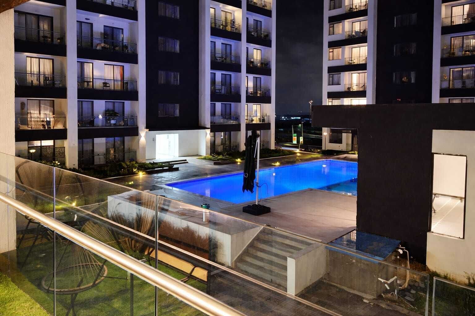 A modern hotel with a rooftop pool, glass balustrades, and multiple balconies.