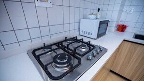 A kitchen with a gas stove, a microwave, and wooden cabinets.