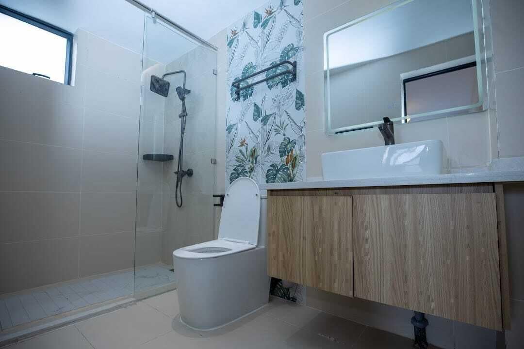 Un baño moderno con cabina de ducha de vidrio, inodoro y tocador con espejo.