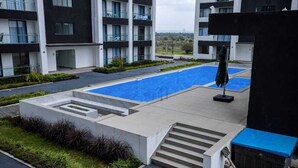 A modern building with a swimming pool, outdoor seating, and a staircase leading to the entrance.