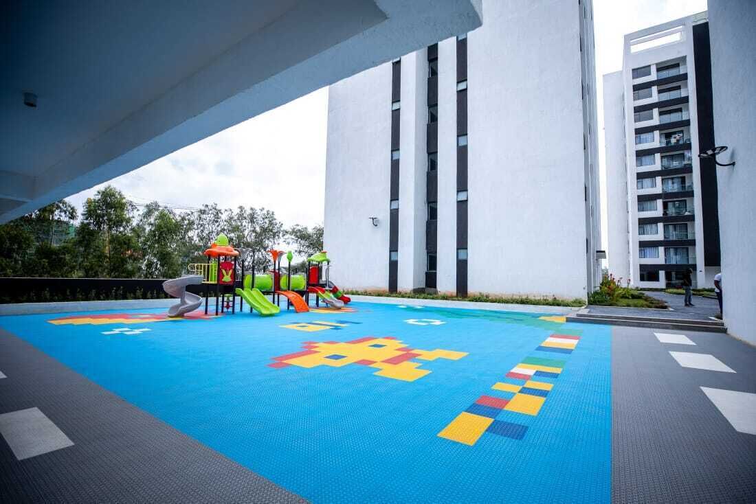 Um parquinho no terraço com escorregadores e estruturas de escalada, cercado por edifícios altos.