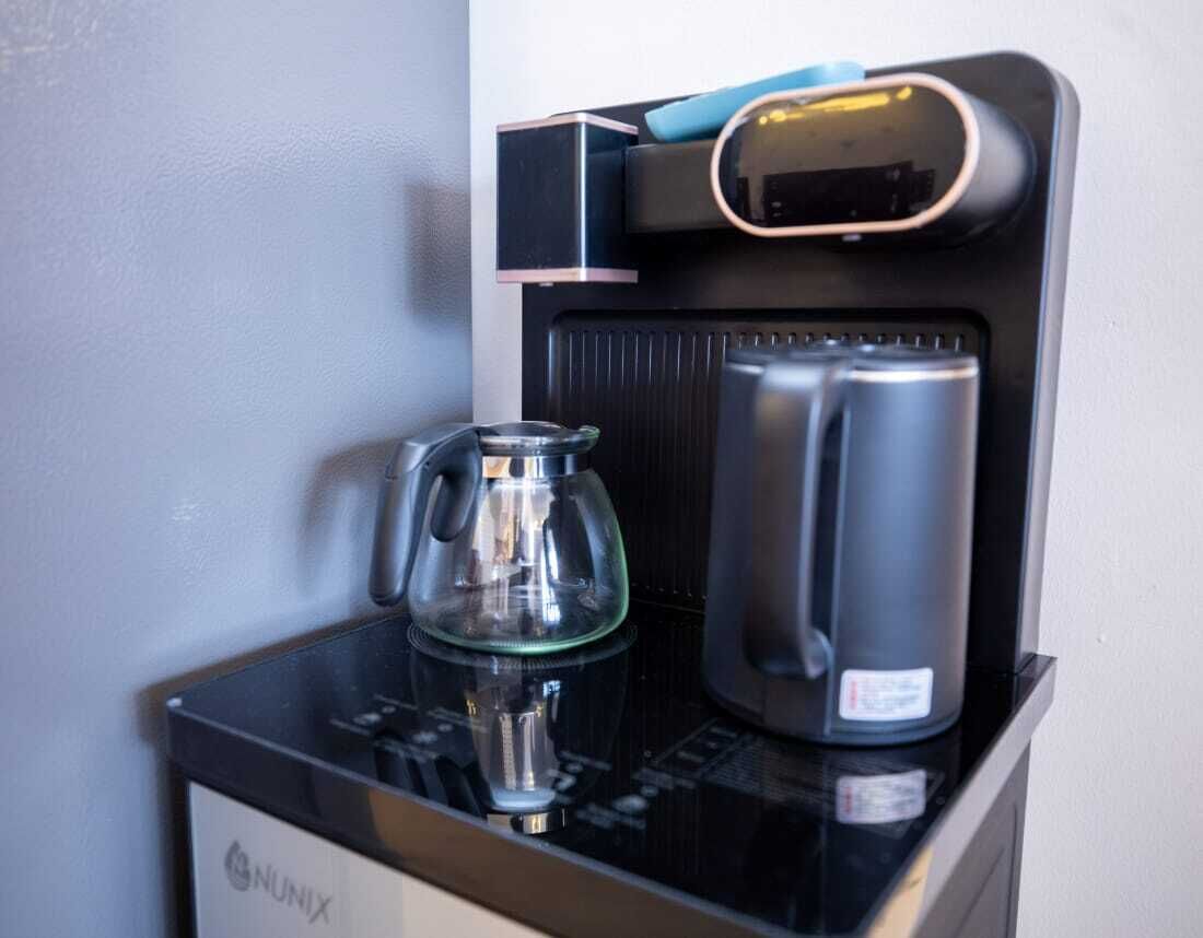 Una máquina de café NUNIX con jarra de vidrio y recipiente negro para café.